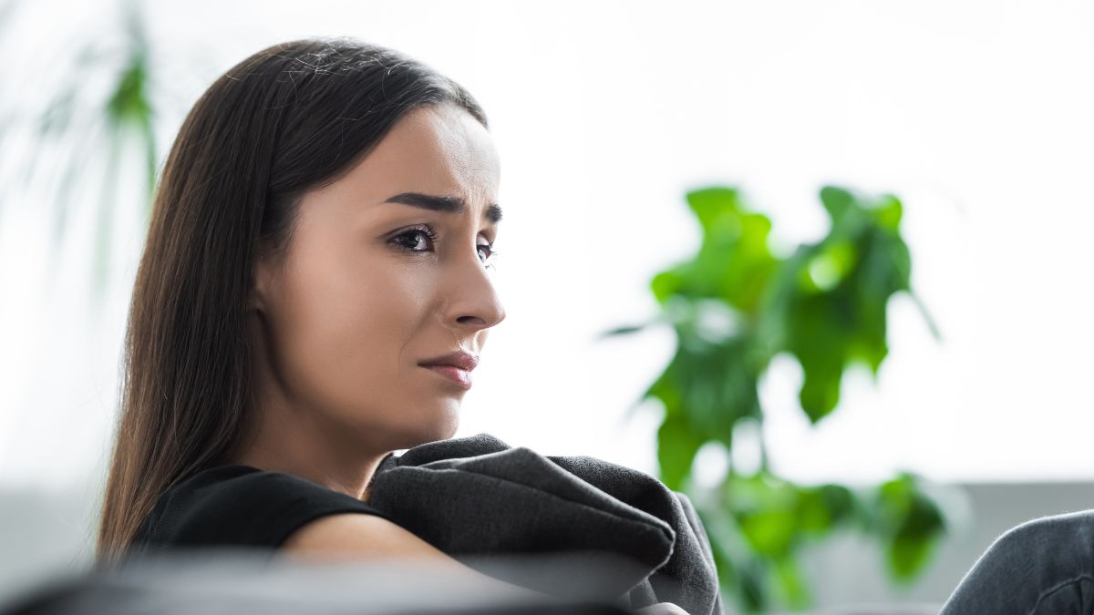 upset woman about to cry sitting on couch