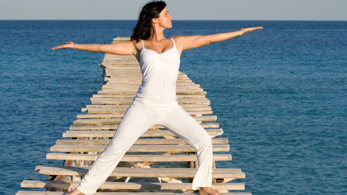 woman doing yoga on dock over water