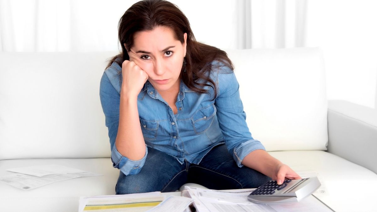 woman leaning on hand looking stressed with bills and calculator