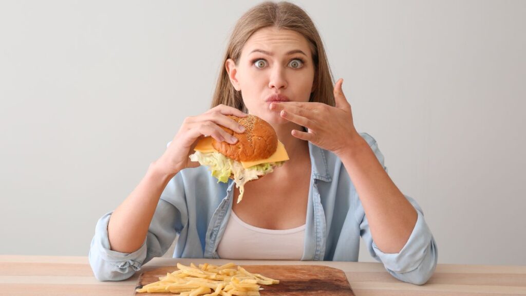 woman looking surprised eating a burger