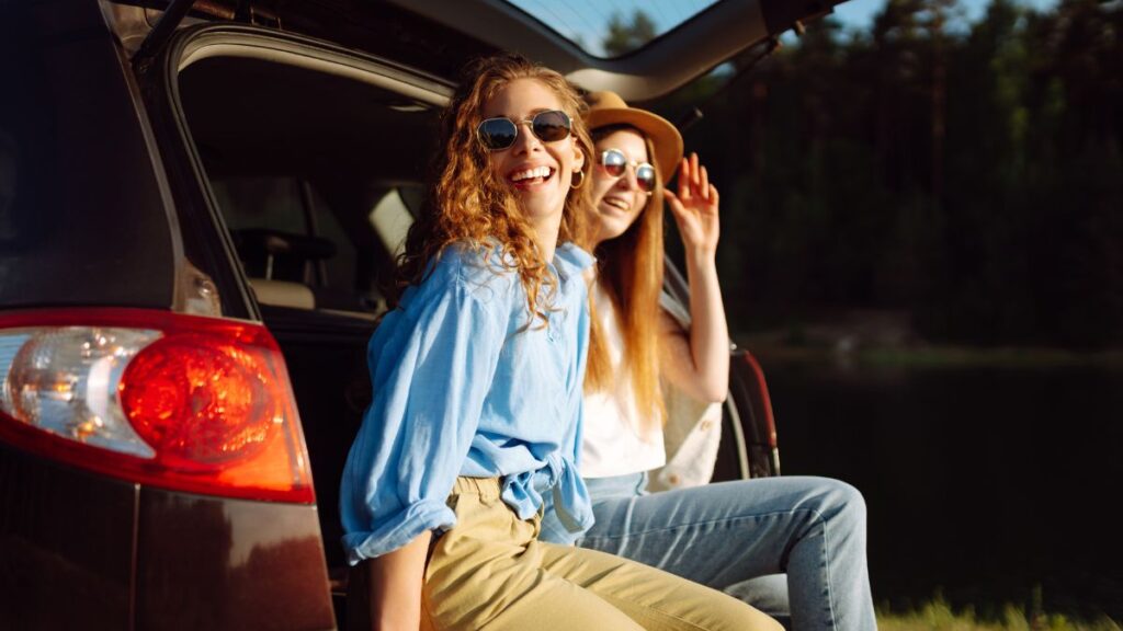 women sitting in the back of an suv smiling on a road trip