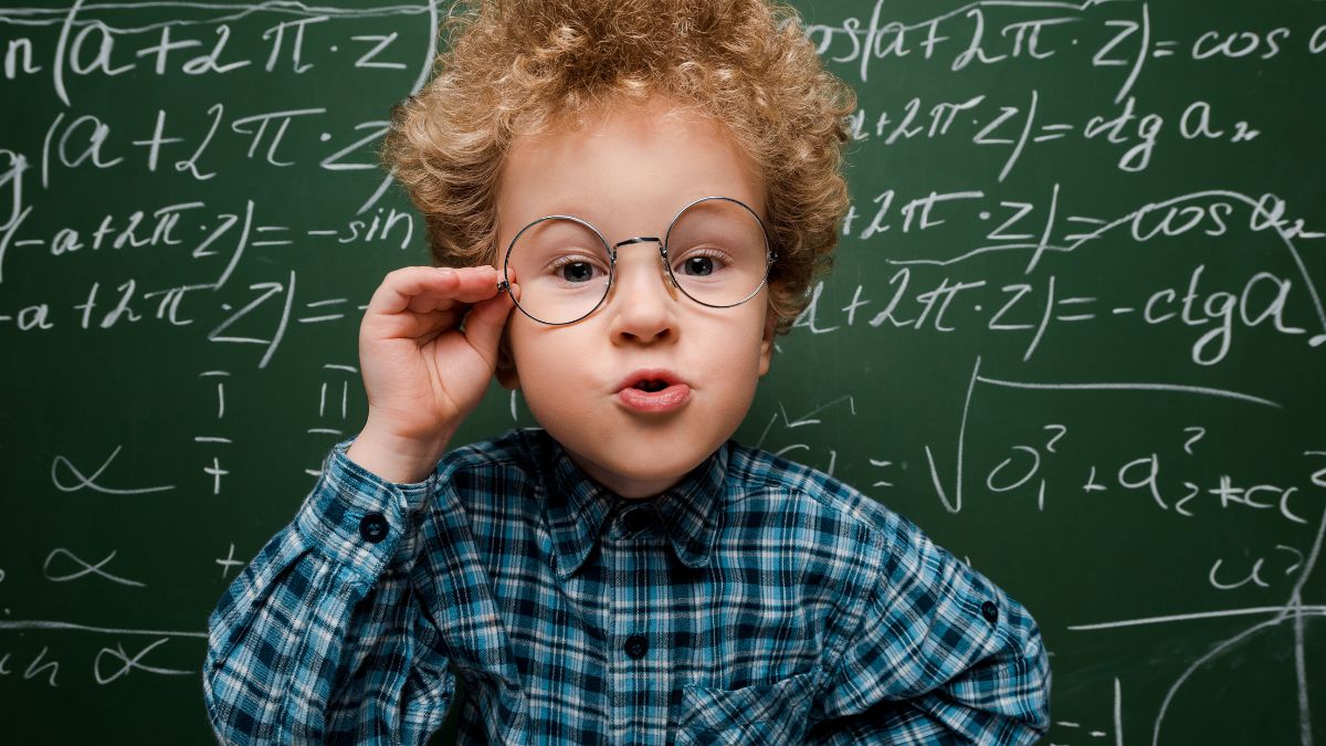 boy with glasses infront of a chalk board with math equations