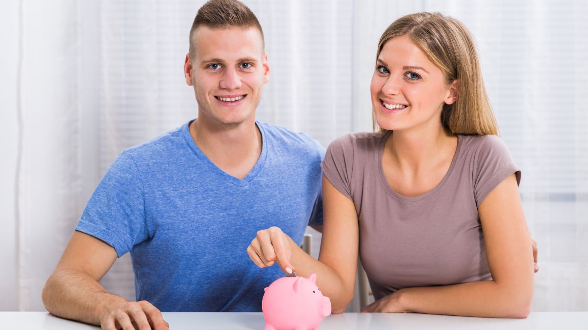 couple saving money in piggy bank smiling