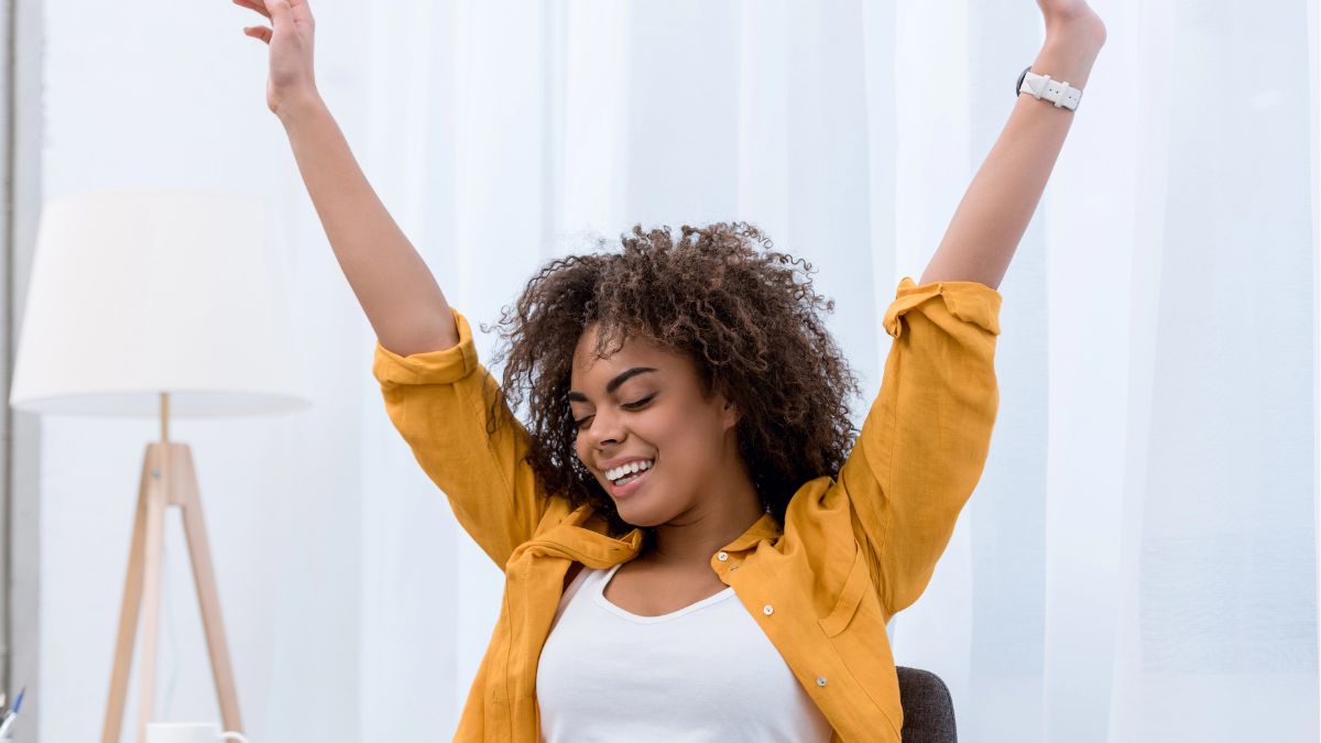 excited woman with hands up at desk