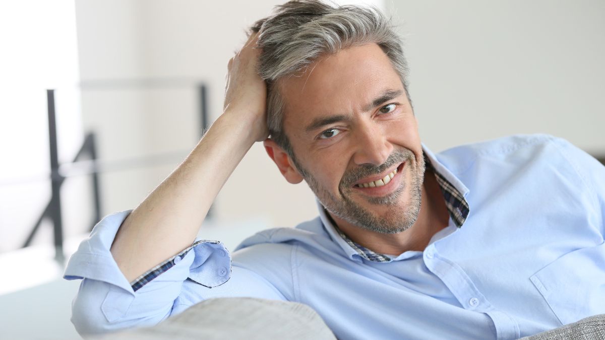 happy man sitting on couch leaning on hand