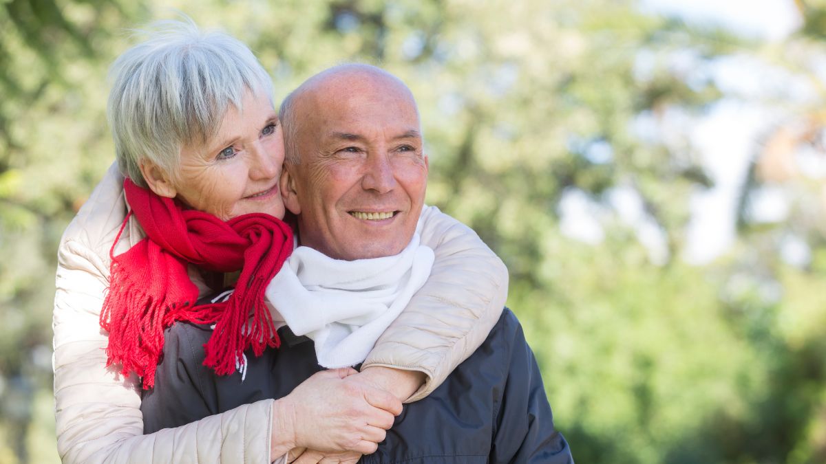 happy retired couple hugging outside