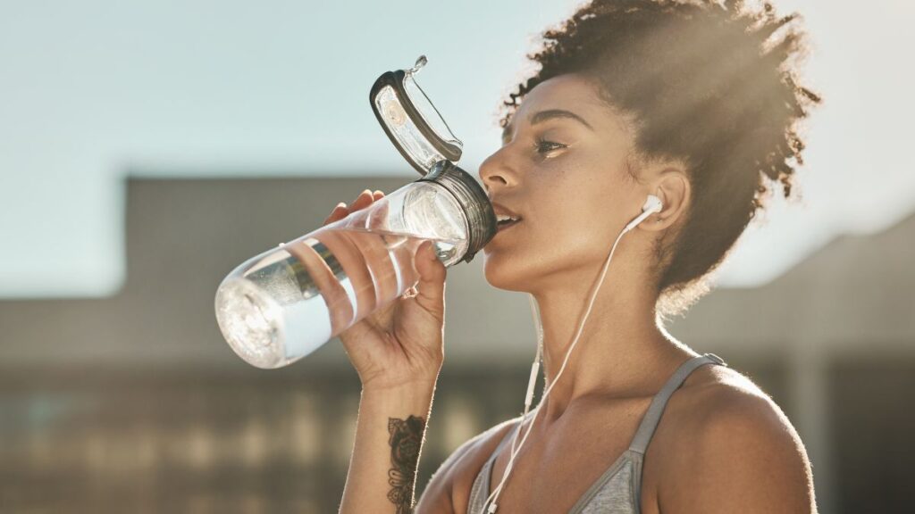 healthy woman with headphones drinking water