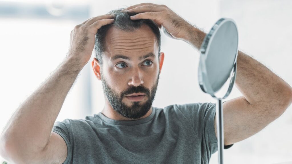 man checking hair mirror