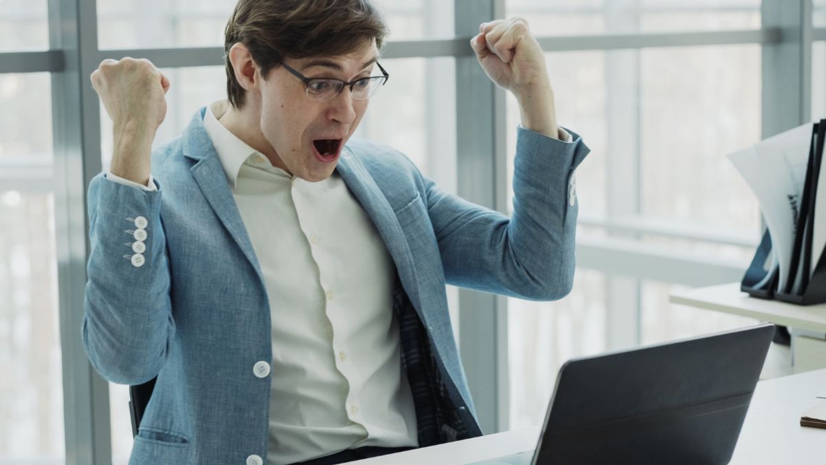 man excited at computer hands up