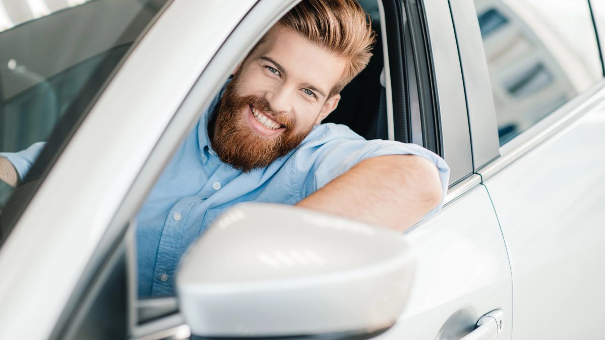 man in silver car smiling