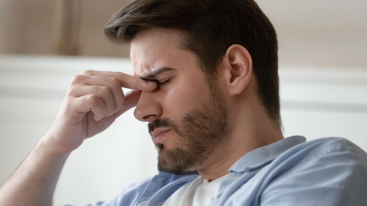 man sitting frustrated with hands on nose