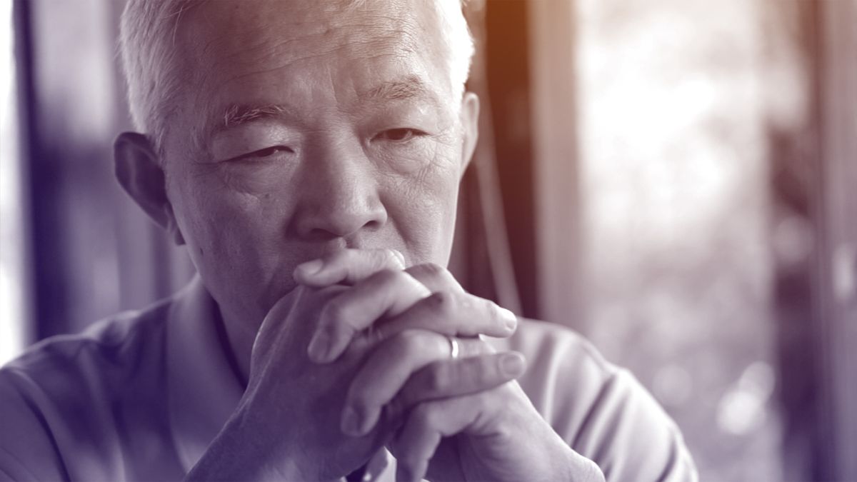 older man looking worries with hands crossed by face