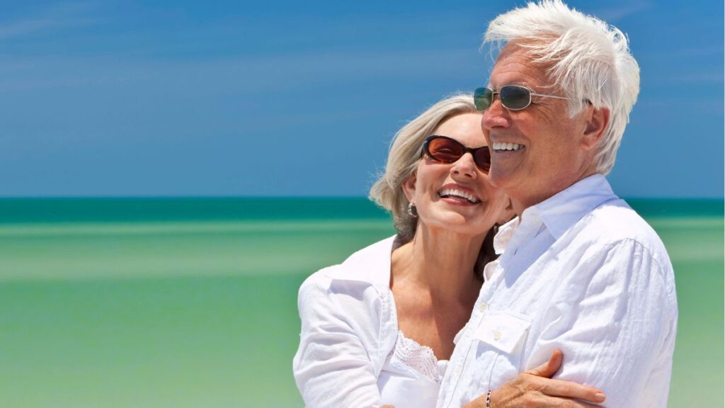 retired couple at the beach smiling -