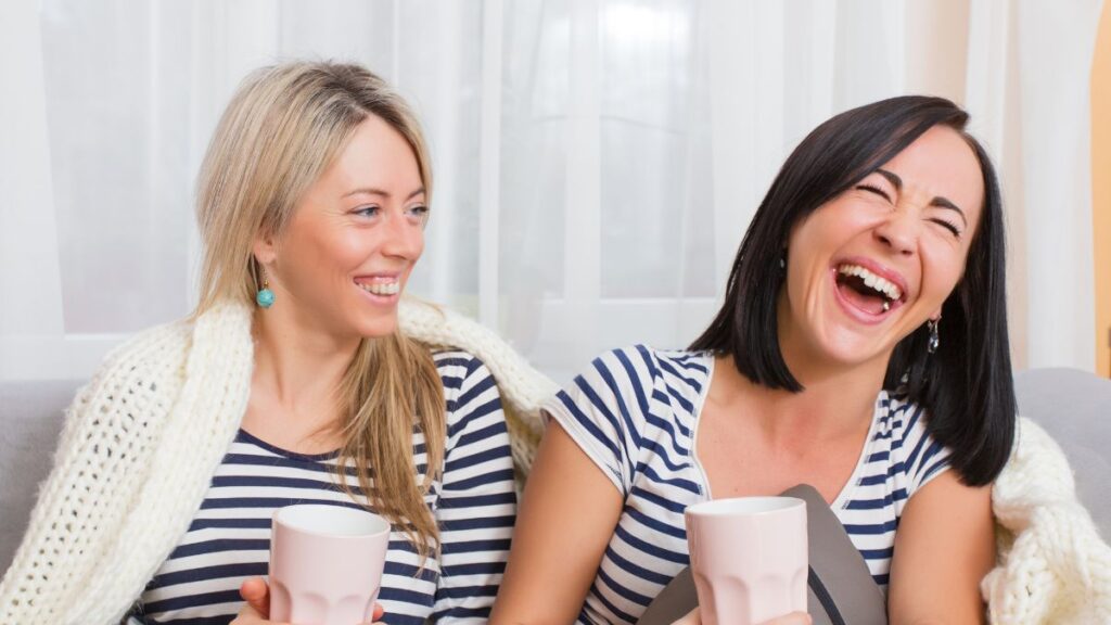 two women laughing while having coffee