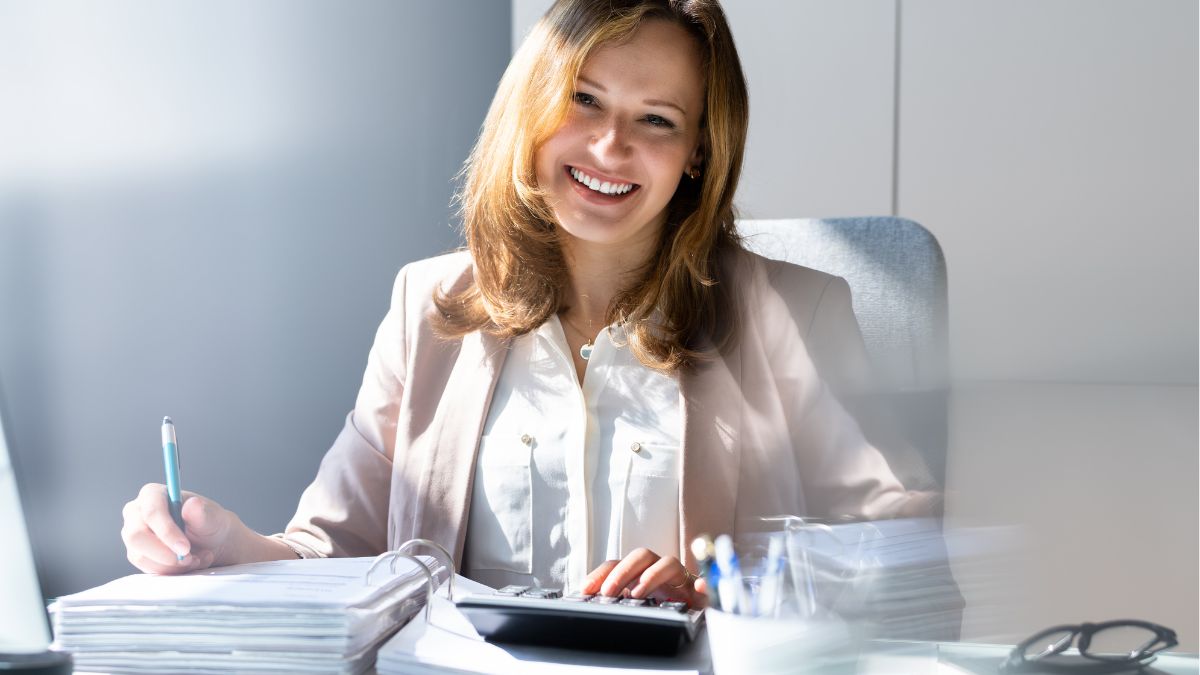 woman at desk doing budget smiling