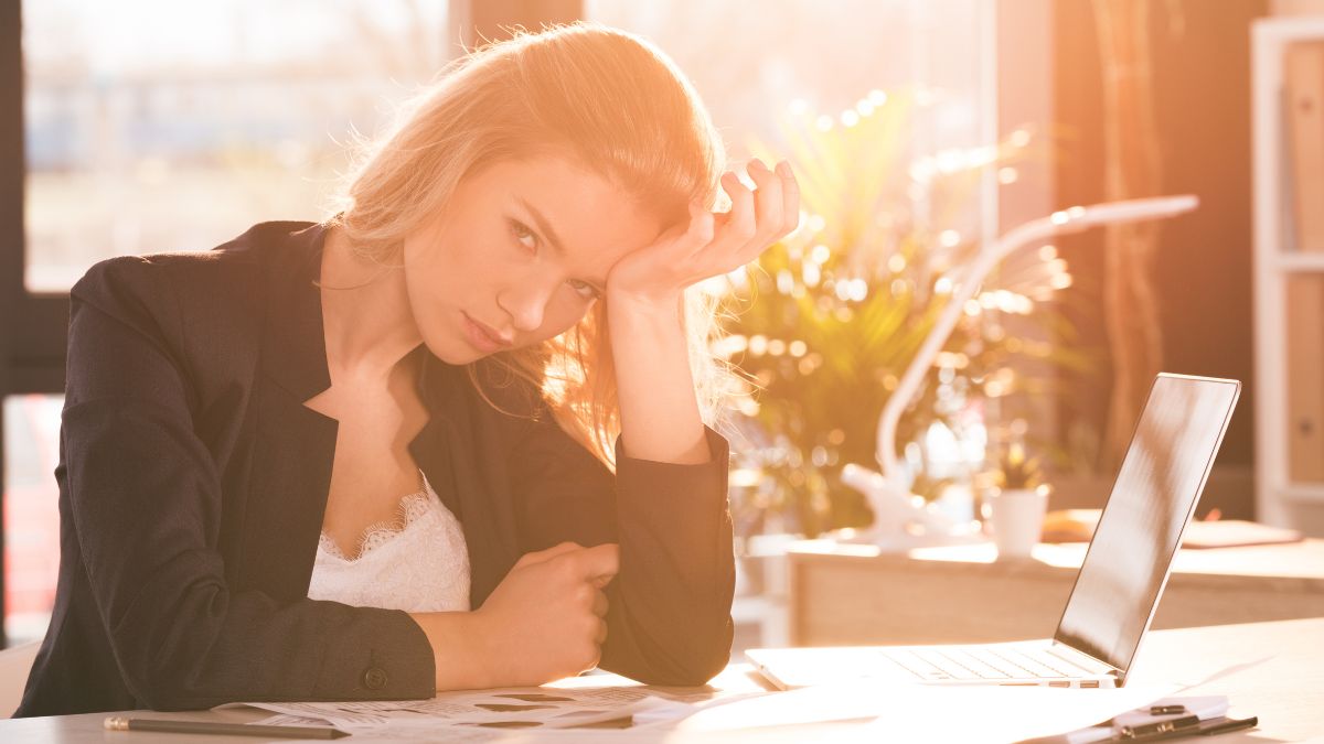 woman at desk looking stressed with hands on head