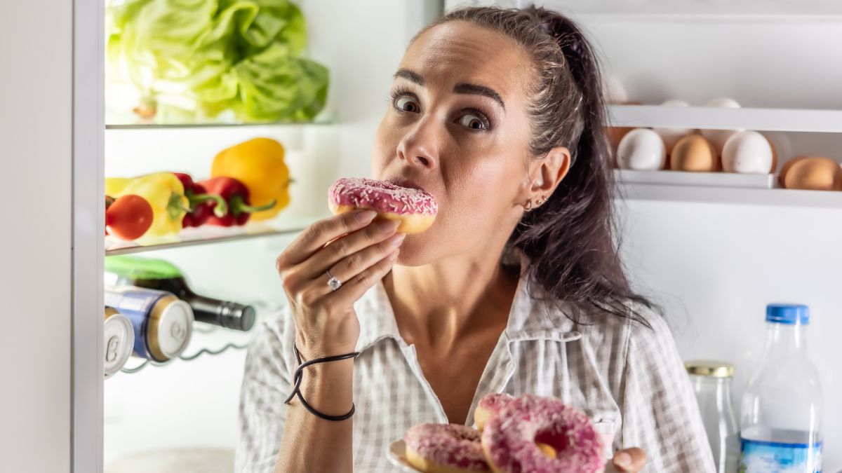 woman eating donuts by fridge