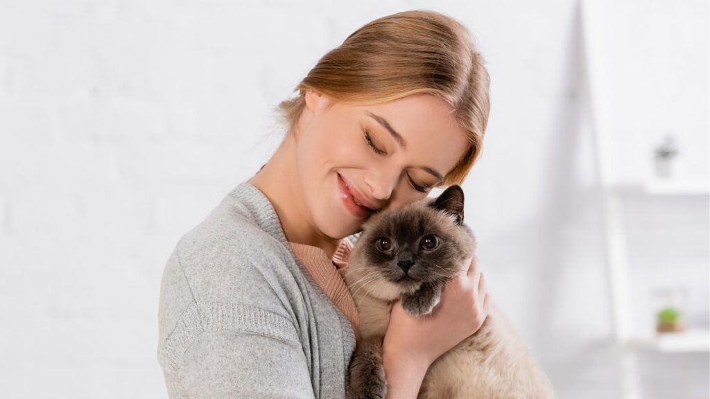 woman hugging Siamese cat