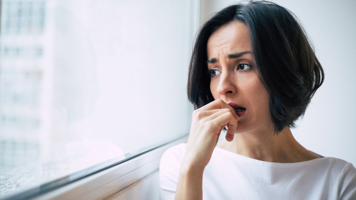 woman looking out the window stressed