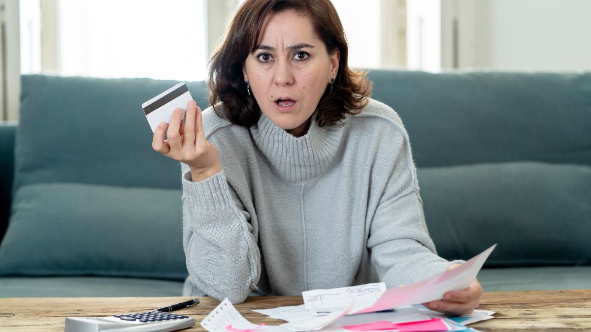 woman looking surprised with credit card and bills