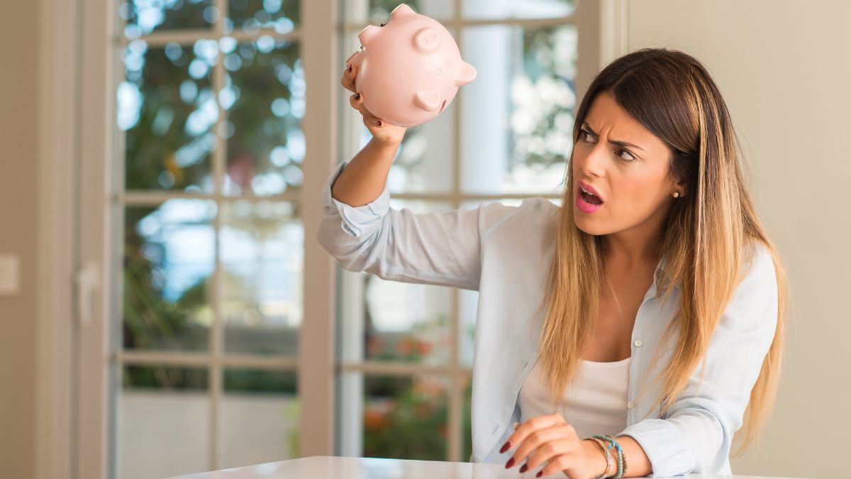 woman looking upset at empty piggy bank