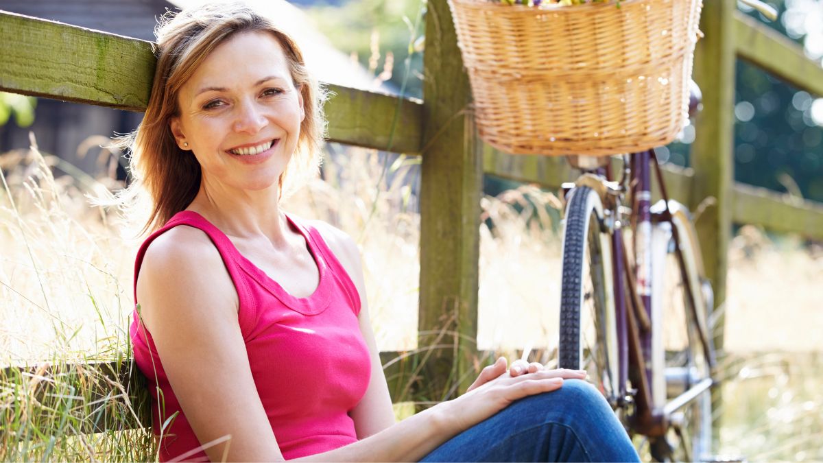 woman sitting on grass with bike and flowers