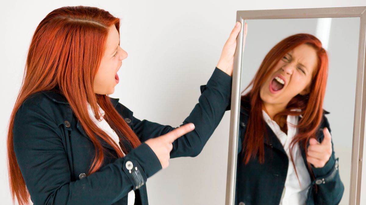 woman with red hair pointing to herself in the mirror