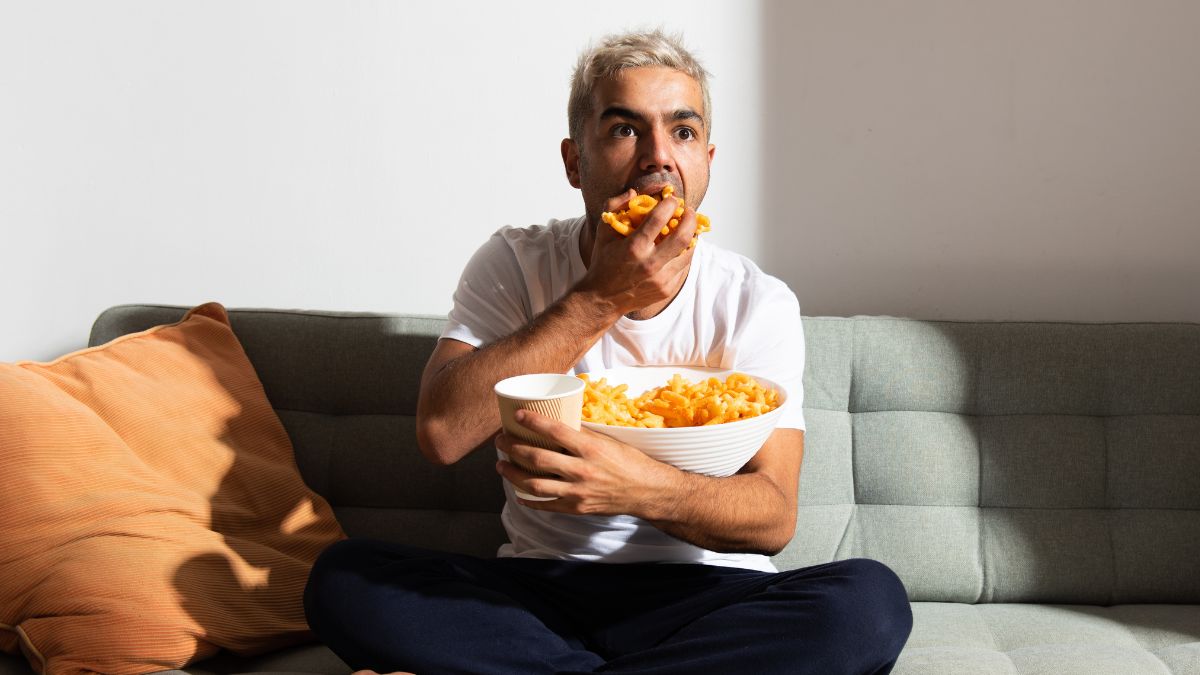 Man on a couch with a big bowl of cheesies