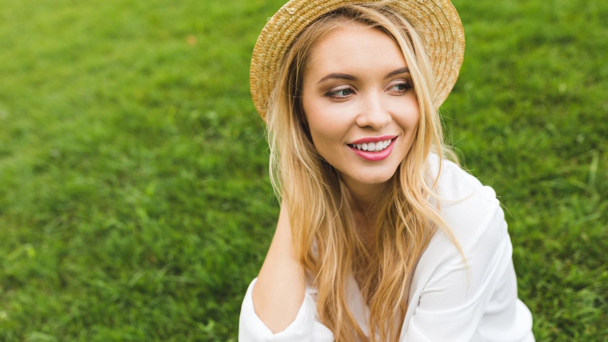 happy woman with straw hat in a field smiling