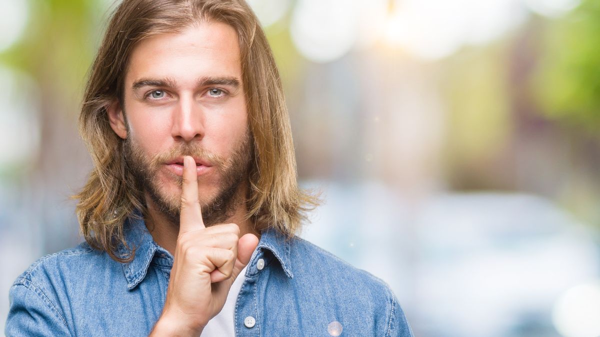 man showing shh with finger outside