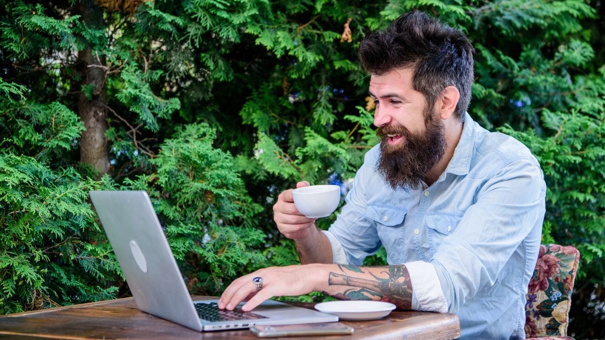 man working on computer outside with coffee