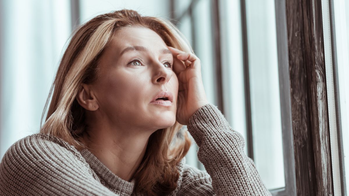 woman looking stressed and confused with hand on head looking up