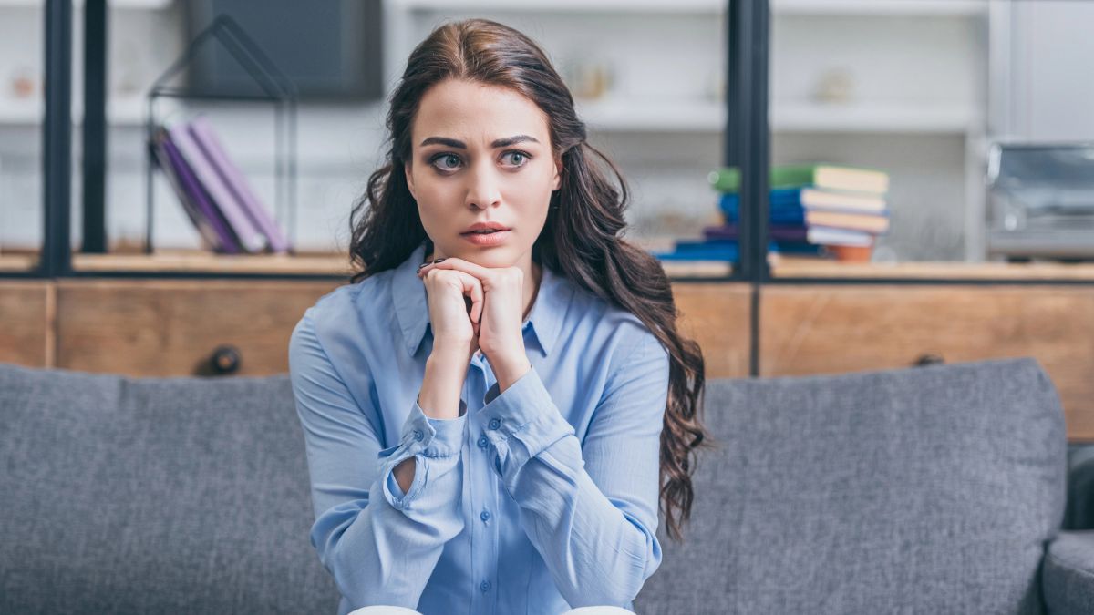 woman looking uncomfortable sitting on the couch