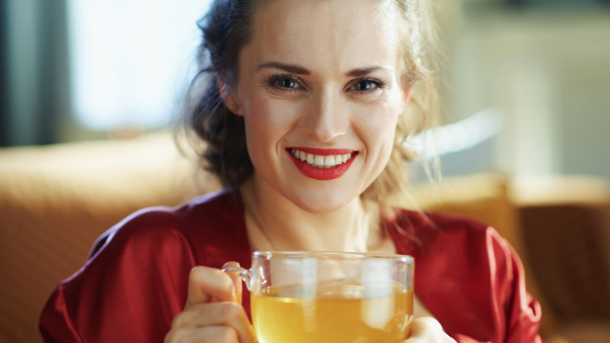 woman smiling with a mug of green tea