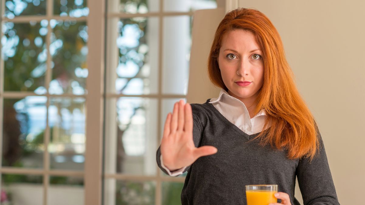 woman with hand up showing stop with juice